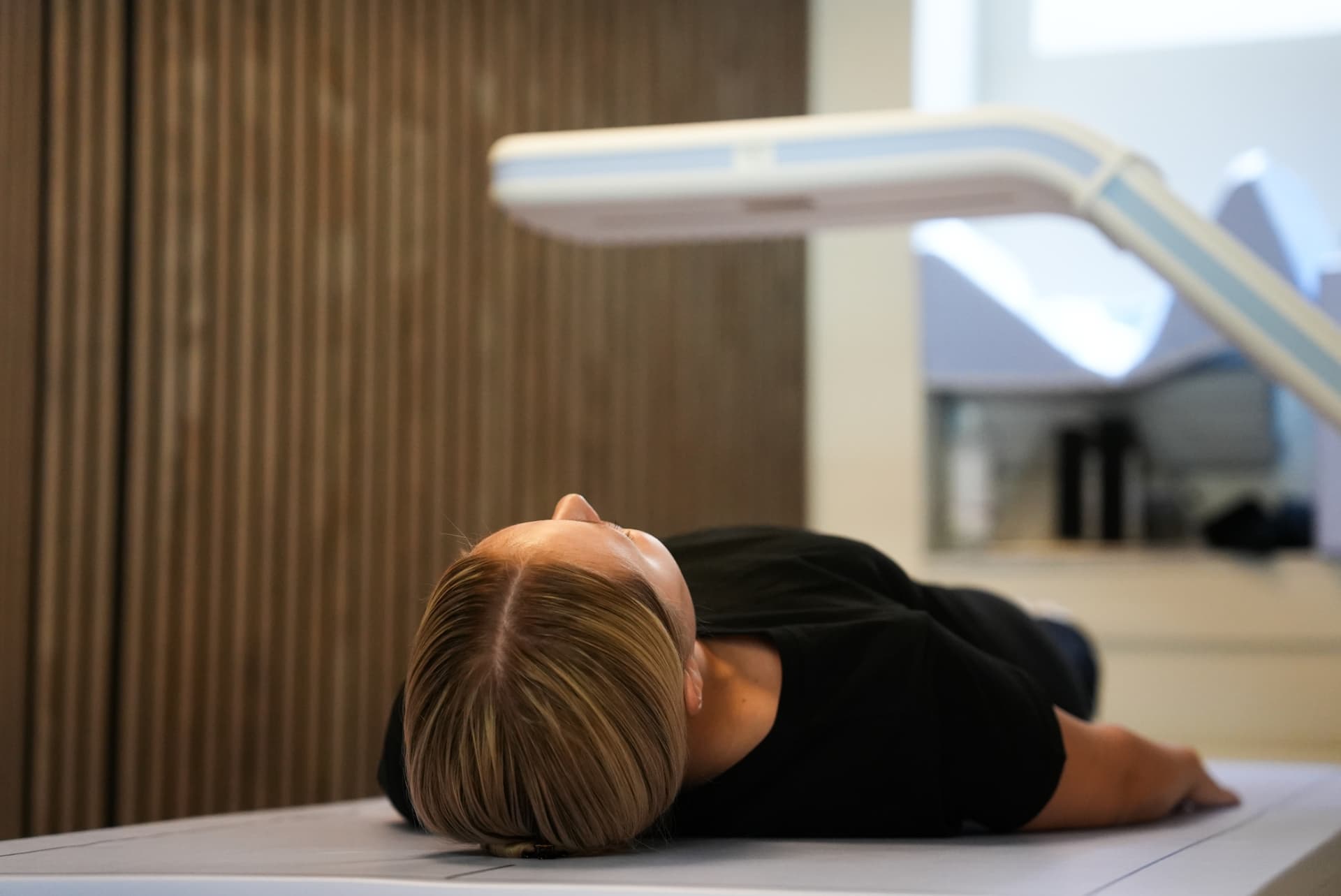 DEXA-undersökning från sidan med scannerarmen ovanför patienten
