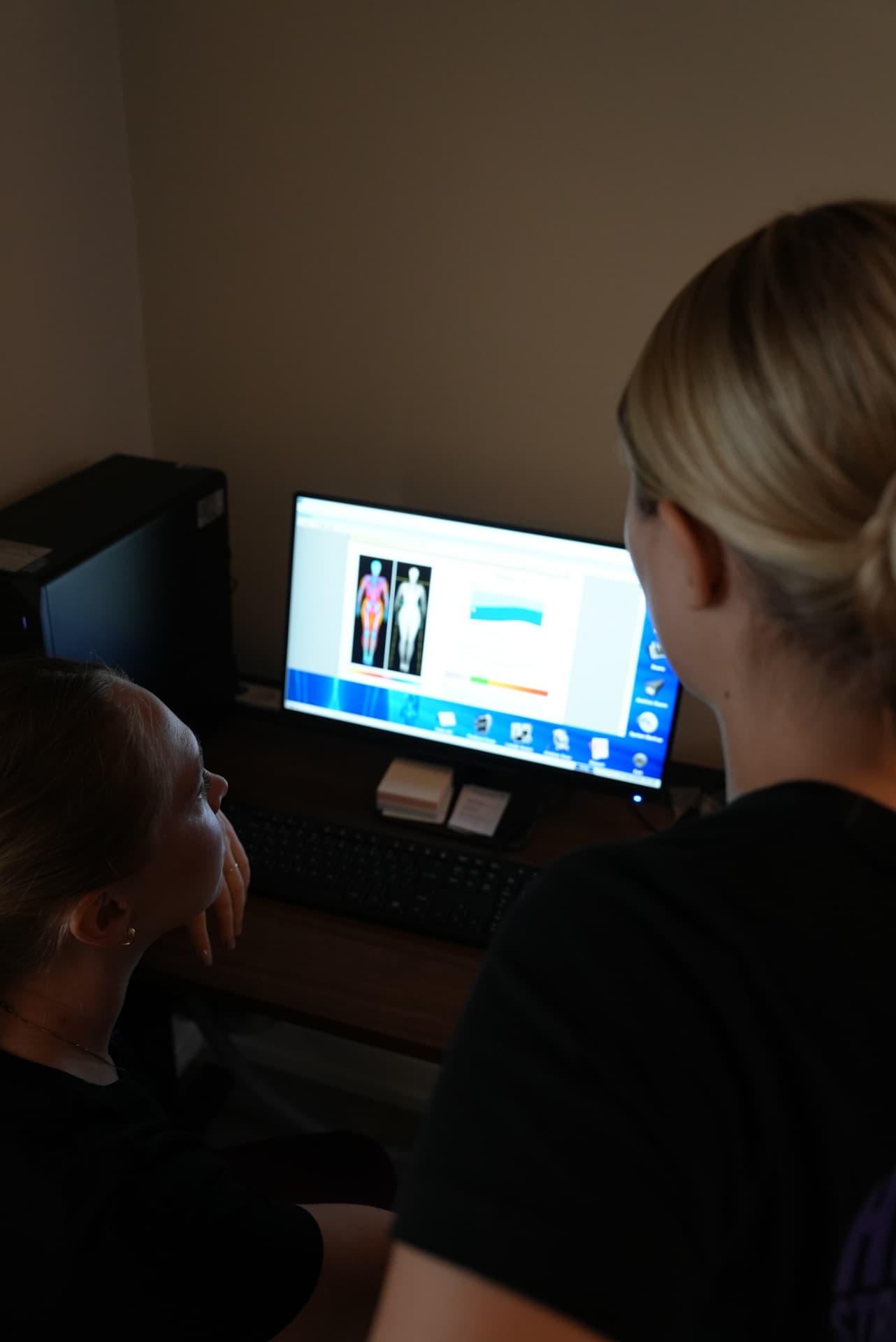 Kliniker som går igenom en färgkodad DEXA-rapport för kroppssammansättning med en patient